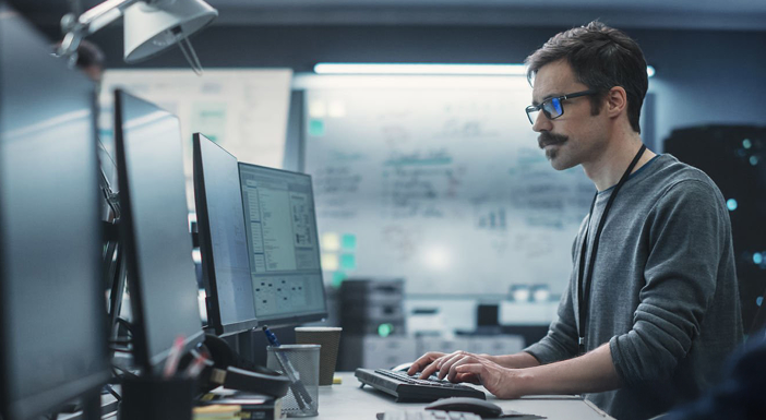 Man working at computer in modern office with whiteboard.